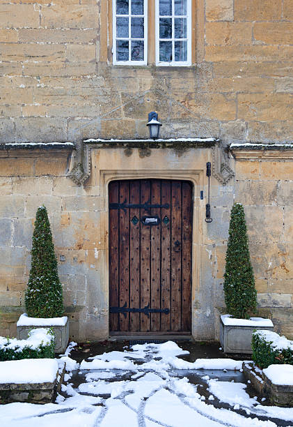 Pretty period property doorway with topiary box trees and snow, Broadway, Worcestershire, England.