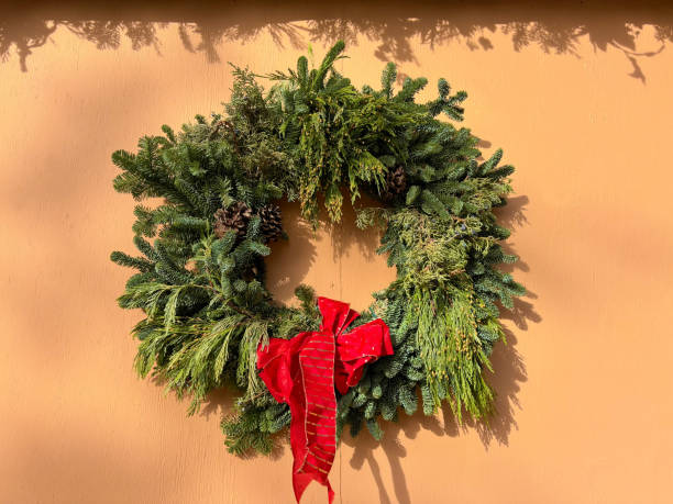 istock Green Christmas Wreath, Red Bow, Sunlit Adobe Wall 1870913498