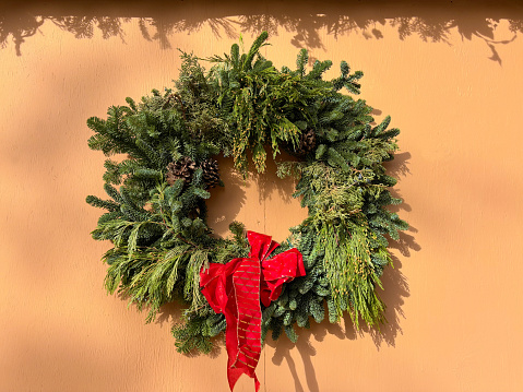 Green Christmas Wreath, Red Bow, Sunlit Adobe Wall. Shot in Santa Fe, NM.
