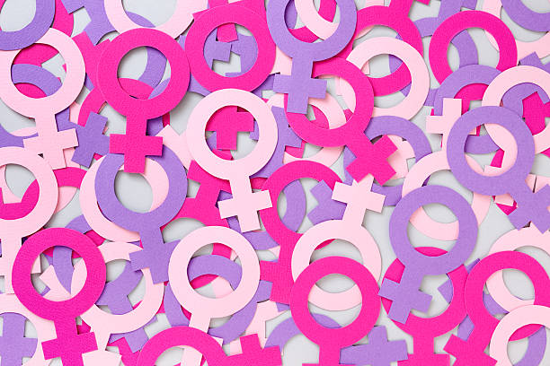 Female symbols background Lots of paper cutouts of male symbols in shades of pink creating a background womens rights stock pictures, royalty-free photos & images