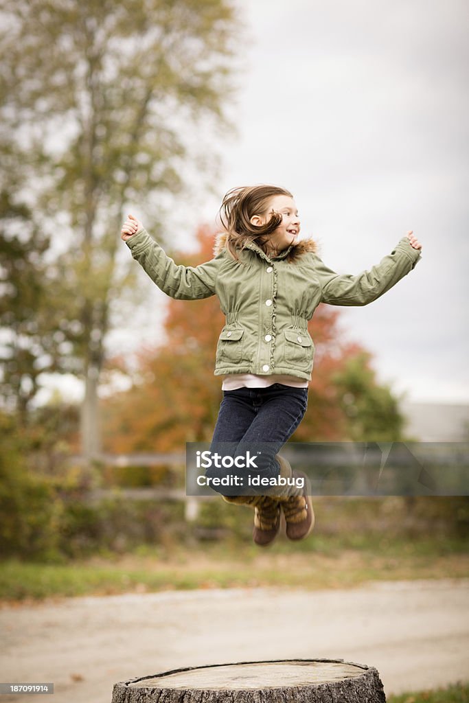 Jovem menina pulando fora em um tronco no outono - Foto de stock de 8-9 Anos royalty-free