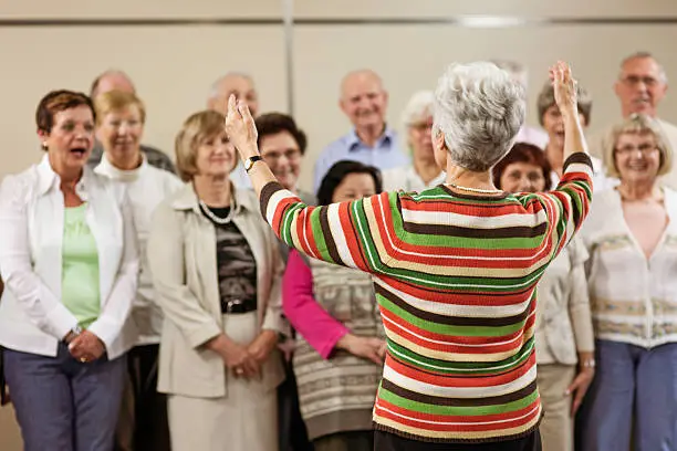 Conductor and seniors' choir in community center.