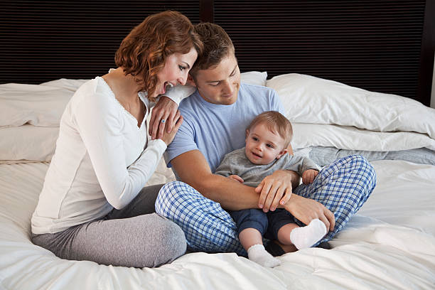 Young family with baby in bedroom Young couple (20s) with baby boy (8 months) relaxing on bed. Sc0601 stock pictures, royalty-free photos & images