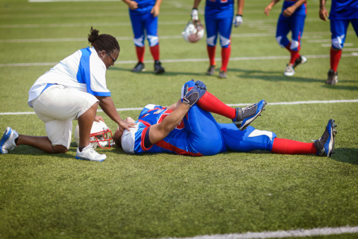 An injured football player on the field being looked after by medical staff.  