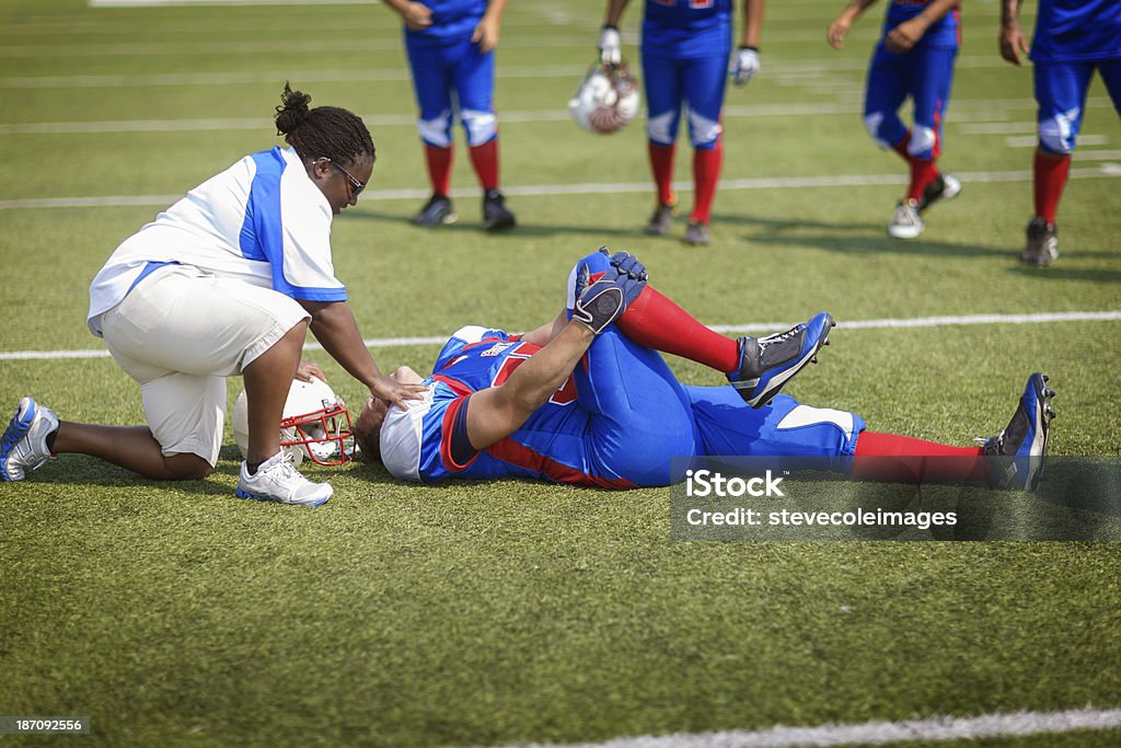 Injured Football Player An injured football player on the field being looked after by medical staff.   Physical Injury Stock Photo