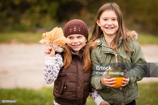 Happy Little Sisters Holding Pumpkin And Autumn Leaf Stock Photo - Download Image Now