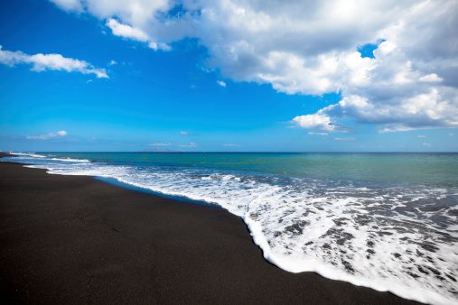 black beach seascape with dramatic cloudscape. perissa beach, santorini, cyclades, greece.