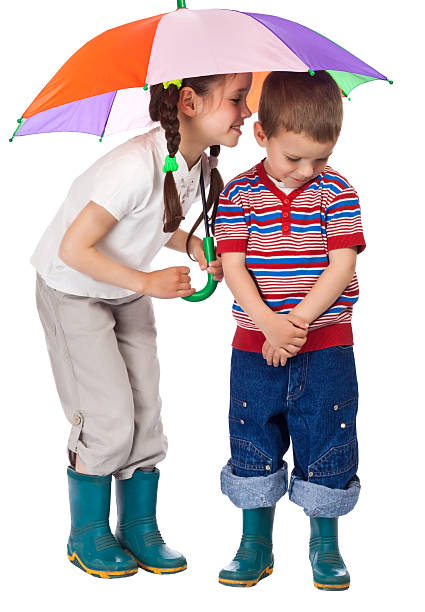 dos niños pequeños en una sombrilla - whispering couple discussion smiling fotografías e imágenes de stock