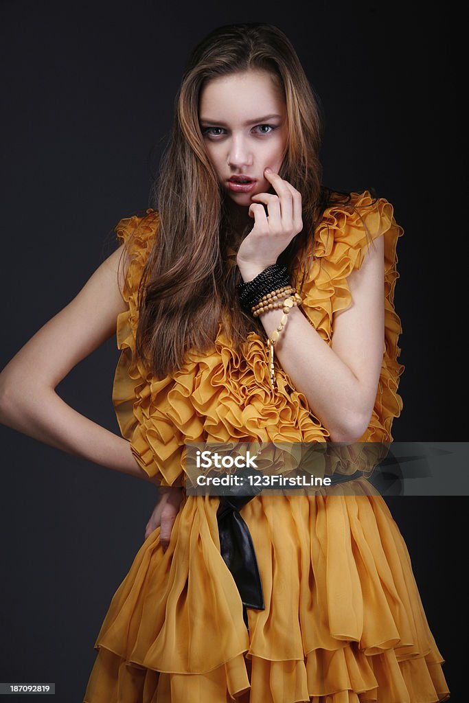 Atraente mulher de vestido amarelo com as mãos perto do rosto dela - Foto de stock de Adulto royalty-free