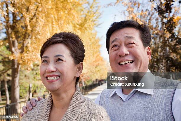 Happy Mature Couple Enjoying The Park In Autumn Stock Photo - Download Image Now - Chinese Ethnicity, Outdoors, Autumn