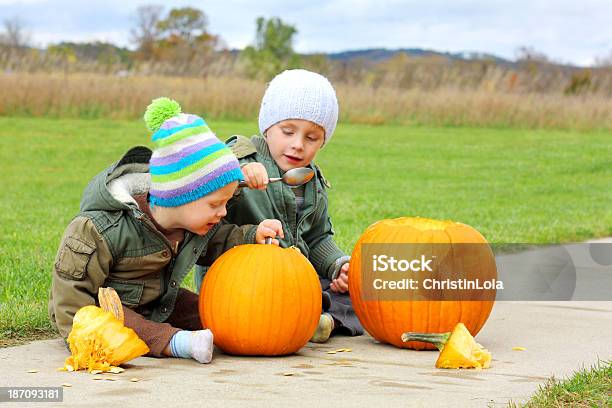 Two Young Children Carving Pumpkins Stock Photo - Download Image Now - 12-17 Months, Assistance, Autumn