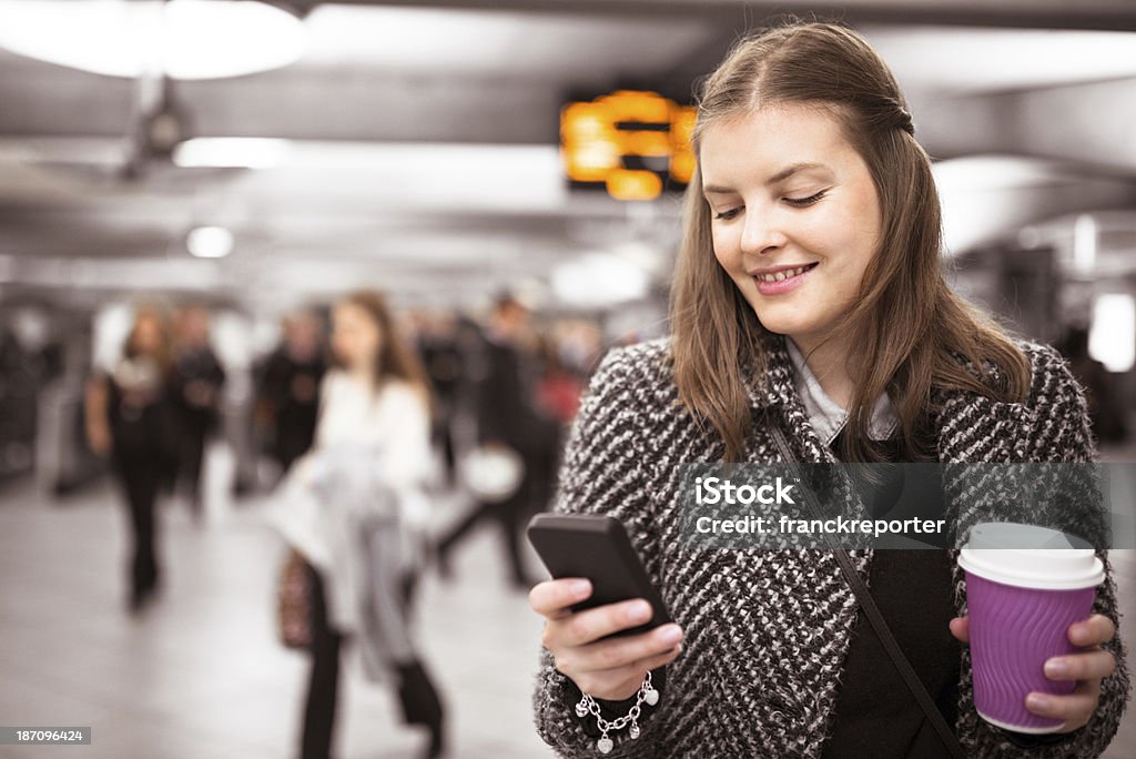 Donna utilizzando un cellulare in metropolitana Stazione della metropolitana - Foto stock royalty-free di Adolescente