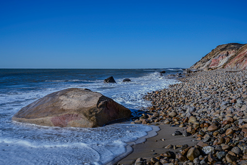 Moshup Beach under Aquinnah Cliffs with white waves rolling in on the glacial rocks and pebbles along the coastal trail in Aquinnah on Marthjas Vineyard, Massachusetts, United States