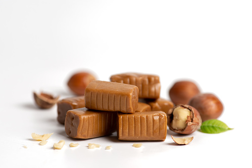 Caramels candy with hazelnuts over white background