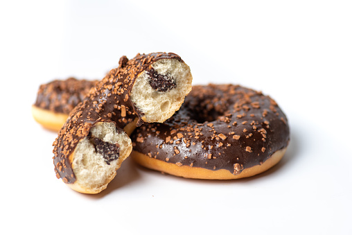 Chocolate covered donuts with nuts. Delicious donuts filled with chocolate cream on a white background