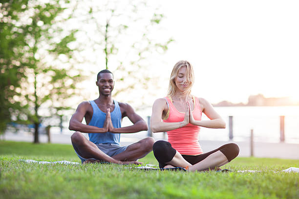 istock Happy young adults meditating on grass at sunset 187098082
