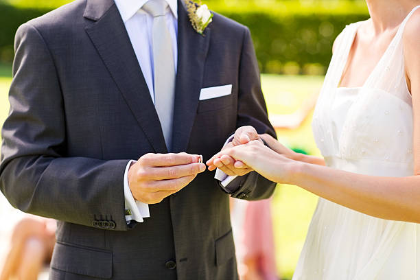 istock Groom Putting Ring On Bride's Finger During Garden Wedding 187099961