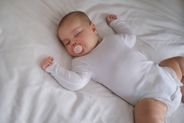 istock Baby Girl Lying on Bed With Pacifier 1871004459