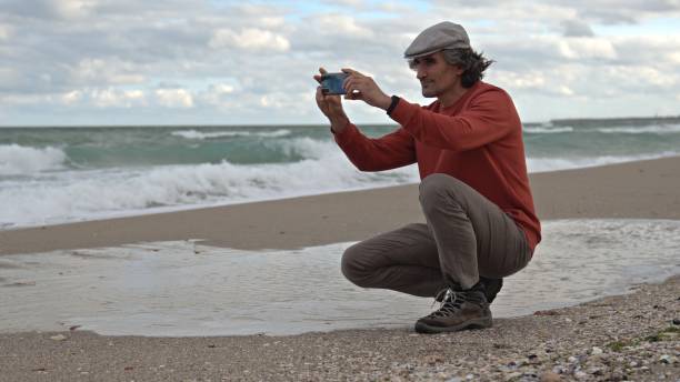 istock Man by the sea, taking selfie and photographing. copy space 1871005012