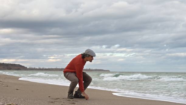 istock Man throwing stones in the sea. People in nature. copy space 1871005014
