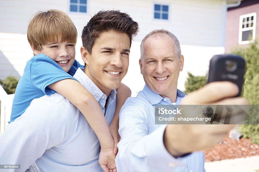 Capturing a family moment A boy sitting on his dad's back as he takes a picture of them with his grandfather 10-11 Years Stock Photo