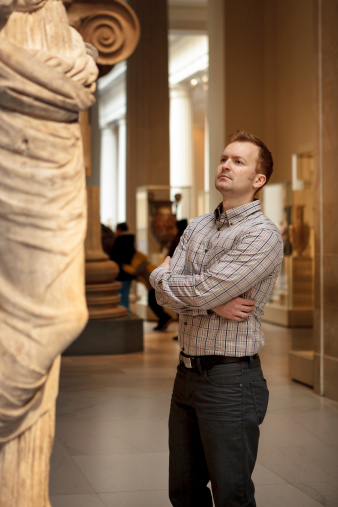 Man at museum looking at fine art statue