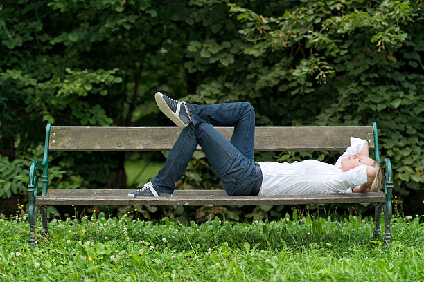 istock Woman laying on park bench sleeping in a park. 187102894