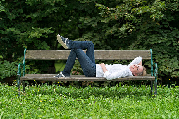 istock attractive blond woman lying on park bench 187103386