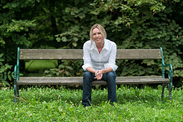 istock attractive blond woman sitting on park bench 187103465