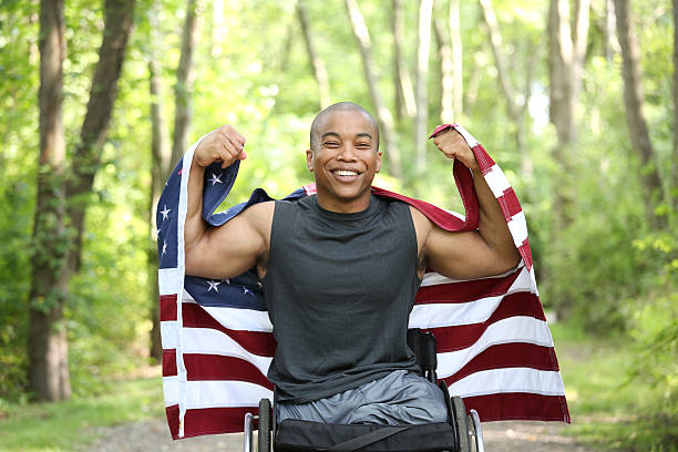 man in wheelchair with flag young male amputee in wheelchair holding american flag paraplegic stock pictures, royalty-free photos & images