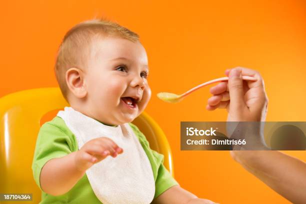 Alimentação Alegre Bebê Em Fundo Laranja - Fotografias de stock e mais imagens de Bebé - Bebé, Alimentar, Comer