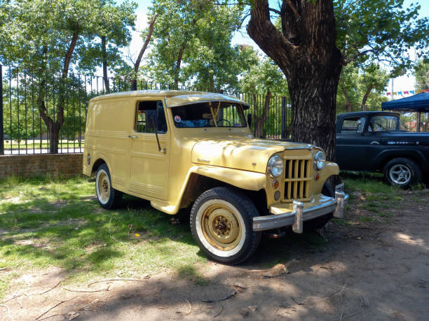 фургон jeep willis utilitario около 1960 года под деревом на выставке классических автомобилей в парке - utilitario стоковые фото и изображения