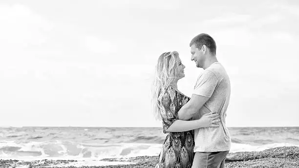 Photo of monotone shot of happy couple in love on the beach