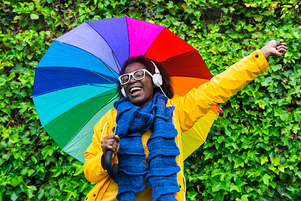 cantare e musica sotto la pioggia. - candid women african descent umbrella foto e immagini stock