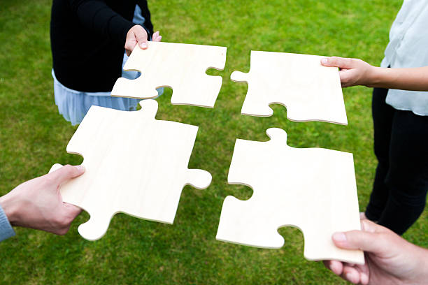 istock Four people connecting their piece of a jigsaw puzzle 187106328