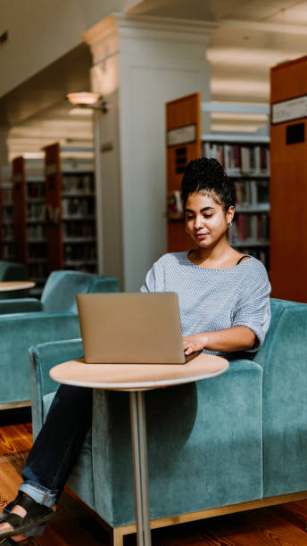 istock Multiracial woman in her 20’s uses a laptop computer inside a library or bookstore 1871069453