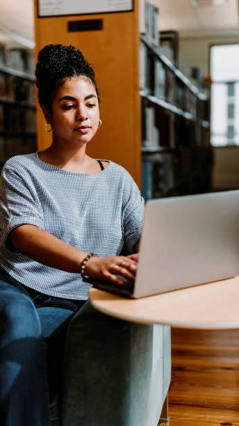 istock Multiracial woman in her 20’s uses a laptop computer inside a library or bookstore 1871077552