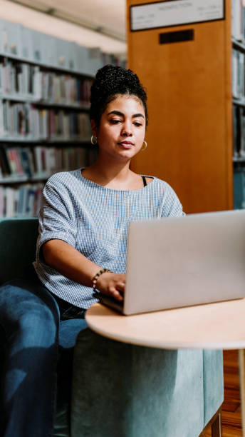 istock Multiracial woman in her 20’s uses a laptop computer inside a library or bookstore 1871078575