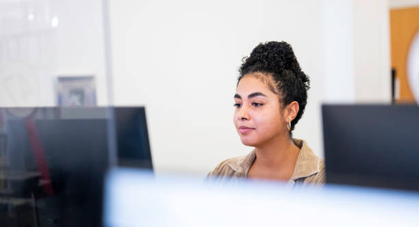 istock Mixed race young woman uses a desktop computer at a public library or on a university campus 1871080394