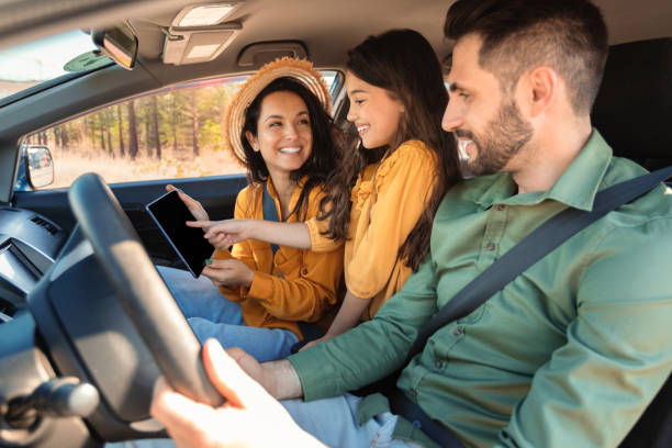 счастливая семья с дочерью, сидящей в машине и использующей цифровой планшет, сверяющейся с онлайн-картами - two parent family technology mobility men стоковые фото и изображения