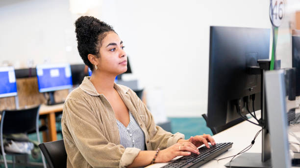 istock Mixed race young woman uses a desktop computer at a public library or on a university campus 1871081598