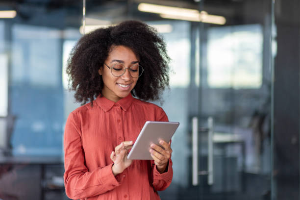 istock Young successful smiling female programmer inside office at workplace, satisfied woman holding tablet computer in hands, testing new software, business woman with curly hair and shirt 1871081800