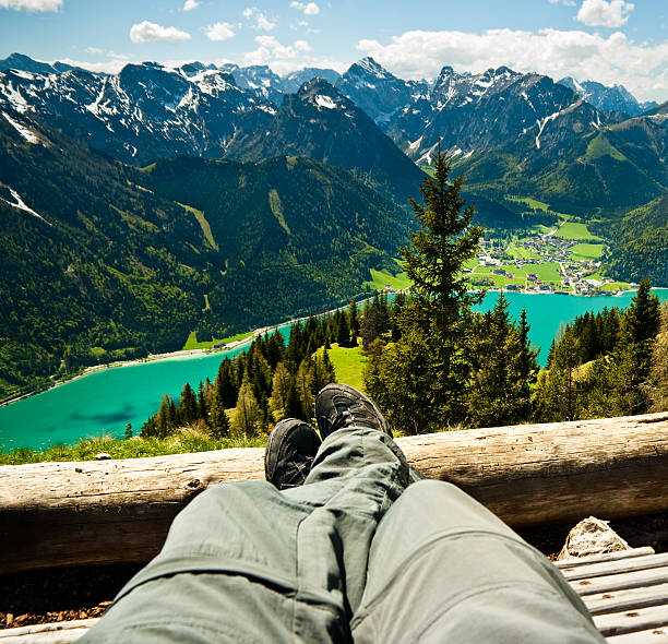 Tired hiker relaxing on the top of the mountain with beautiful view on the lake Achensee in Tirol, Austria
