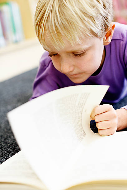 istock Cute little girl concentrates on reading in library 187108824
