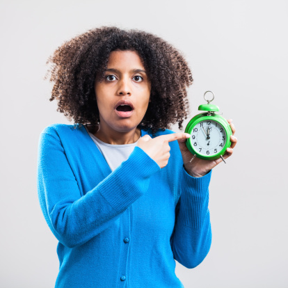 Woman pointing to clock showing five to twelve time