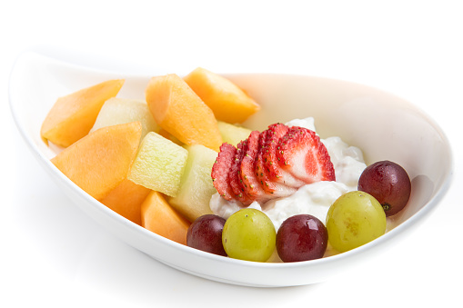 Fruit salad and cottage cheese on white background