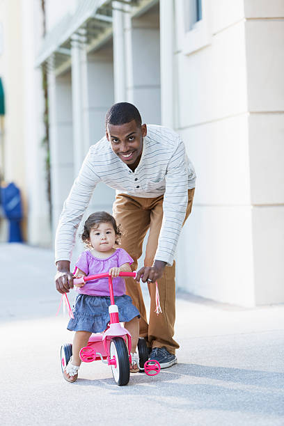 istock Father helping toddler ride tricycle 187109781
