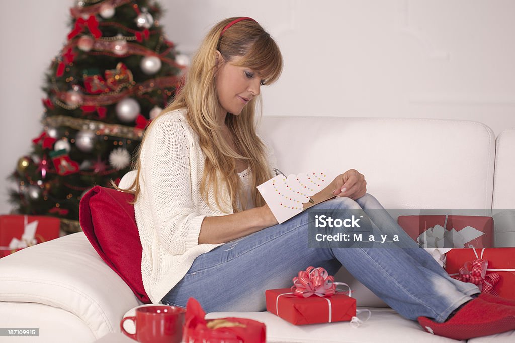 Writing a Christmas greeting cards. Beautiful women by the Christmas tree,writing Christmas greeting card. Christmas Card Stock Photo