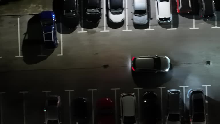 AERIAL Directly Above Drone Shot of Car Moving Out of Parking Lot at Night in Koper City