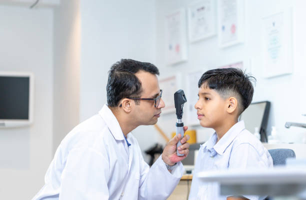 istock Optometrist doing sight testing for child patient in clinic, Indian child choosing eyeglasses in optics store, Boy doing eye test checking examination with optometrist in optical shop 1871113177